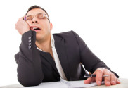 exhausted businessman sleeping at his desk yawning with pencil in hand